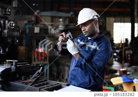 Professional male industrial worker in white hard hat working at manufacturing 105183282