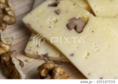Sliced piece of milk cheese with walnuts Sliced piece of milk cheese with walnuts 105187559