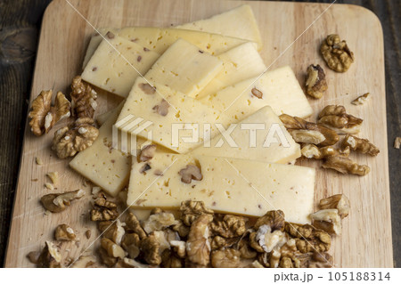 Sliced piece of milk cheese with walnuts 105188314