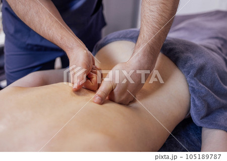 Strong hands of the masseur touch the female client back. 105189787