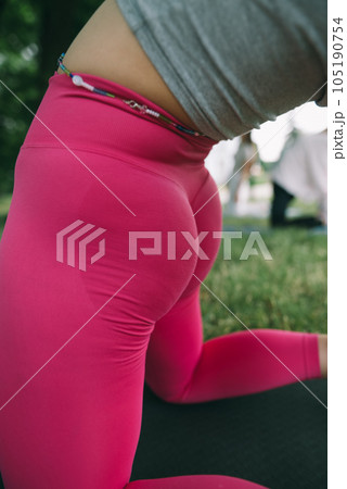 The girl is performing yoga stretches while attending a park yoga session. The girl is performing yoga stretches while attending a park yoga session. 105190754