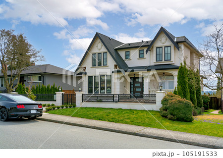 Luxury residential house with a car parked in front on cloudy day 105191533