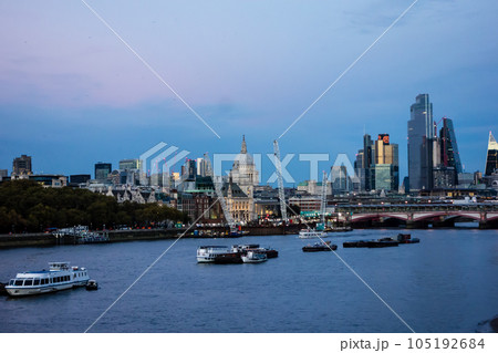 黄昏時のロンドンの街並み　高層ビルの立ち並ぶ間を流れるテームズ川と行きかう様々な船 105192684