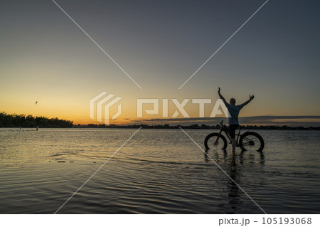 sunrise silhouette of a man with a fat mountain bike on a lake shore, Boyd Lake State Park in northern Colorado sunrise silhouette of a man with a fat mountain bike on a lake shore, Boyd Lake State Park in northern Colorado 105193068