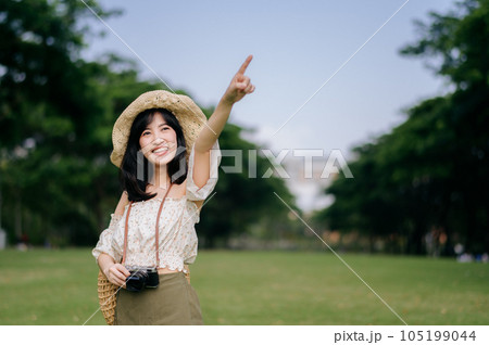 Portrait of asian young woman traveler with weaving hat and basket and a camera on green public park nature background. Journey trip lifestyle, world travel explorer or Asia summer tourism concept. Portrait of asian young woman traveler with weaving hat and basket and a camera on green public park nature background. Journey trip lifestyle, world travel explorer or Asia summer tourism concept. 105199044
