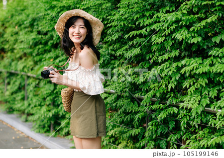 Portrait of asian young woman traveler with weaving hat and basket and a camera on green public park nature background. Journey trip lifestyle, world travel explorer or Asia summer tourism concept. Portrait of asian young woman traveler with weaving hat and basket and a camera on green public park nature background. Journey trip lifestyle, world travel explorer or Asia summer tourism concept. 105199146