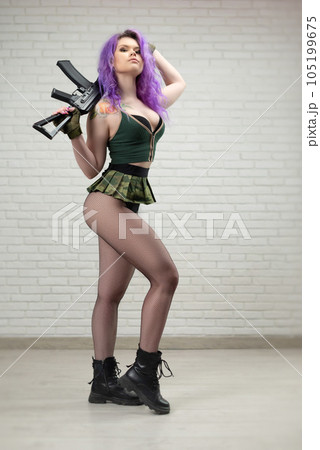 sexy girl with pink hair in a short skirt miliriti with an airsoft gun on a white background of a brick wall 105199675