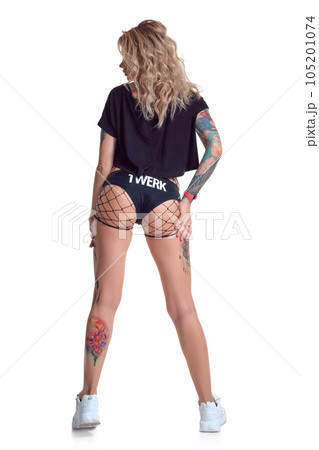 Beautiful blonde dancer woman in booty shorts and fishnet stand backwards isolated on white background 105201074