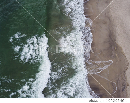a stunning aerial view of the sea, with waves breaking against a sandy beach. a stunning aerial view of the sea, with waves breaking against a sandy beach. 105202464