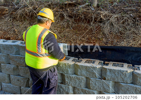 With precision skill construction worker attached concrete block securely to retaining wall. With precision skill construction worker attached concrete block securely to retaining wall. 105202706