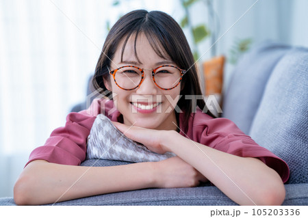 ソファに寝転んでくつろぐ眼鏡の若い女性 ソファに寝転んでくつろぐ眼鏡の若い女性 105203336
