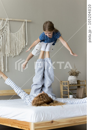 Active strong mother lifting kid in air on feet Active strong mother lifting kid in air on feet 105204810