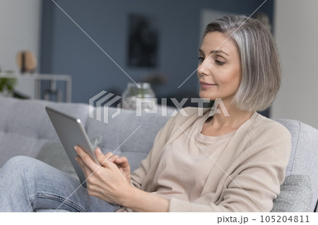 Positive mature freelancer woman using digital device for remote job Positive mature freelancer woman using digital device for remote job 105204811