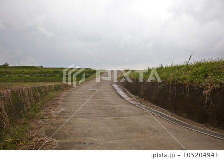 田園風景の中、カーブする1本の坂道【梅雨空】 105204941
