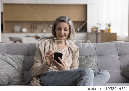 Positive mature grey haired woman enjoying online communication Positive mature grey haired woman enjoying online communication 105204982