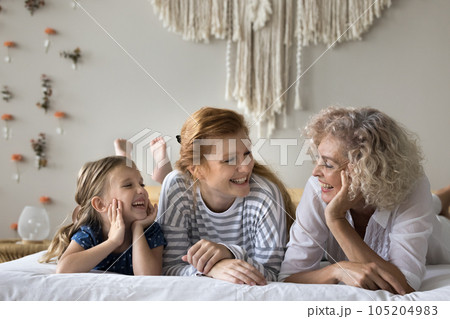 Happy carefree kid, mother and grandmother relaxing on bed Happy carefree kid, mother and grandmother relaxing on bed 105204983
