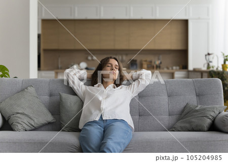 peaceful woman relaxing on comfortable sofa in living room peaceful woman relaxing on comfortable sofa in living room 105204985