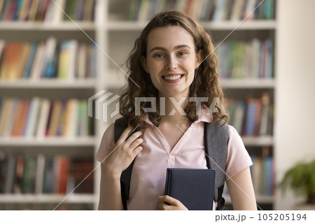 Happy beautiful curly wavy haired student girl adjusting backpack 105205194