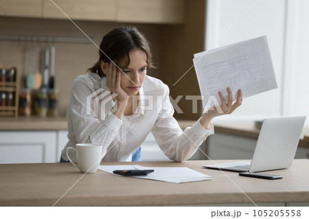 Worried woman feels shocked due to heap of unpaid bills 105205558