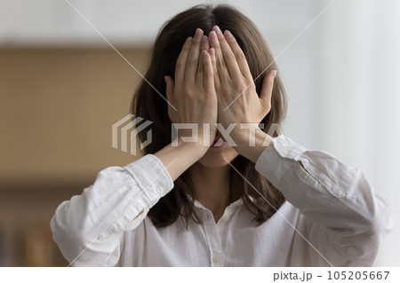 Closeup portrait of young woman hiding her face behind palms 105205667