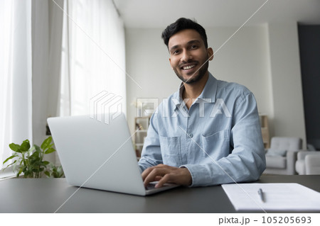 Happy young Indian freelance employee guy working at home Happy young Indian freelance employee guy working at home 105205693