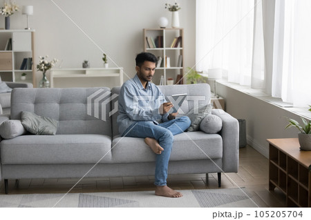 Focused Indian student guy using learning app on tablet Focused Indian student guy using learning app on tablet 105205704