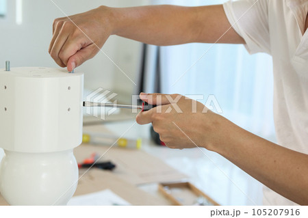 Asian man assembling white table furniture at home Asian man assembling white table furniture at home 105207916