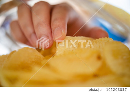 Hand picking potato chips inside snack bag 105208037