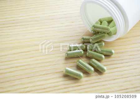 Herbal medicine capsules with bottle on wood table 105208509