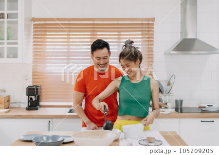 Husband looking at wife who cooking lunch for him. Happy couple in kitchen. Husband looking at wife who cooking lunch for him. Happy couple in kitchen. 105209205
