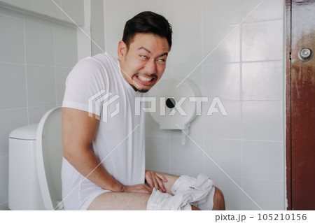 Funny face man pushing poop in the toilet as he has constipation. Funny face man pushing poop in the toilet as he has constipation. 105210156