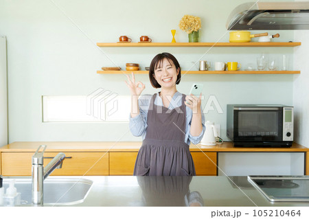 キッチンでスマホを見る女性 105210464