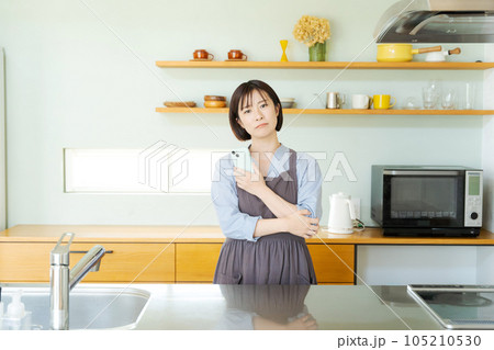 キッチンでスマホを見る女性 105210530
