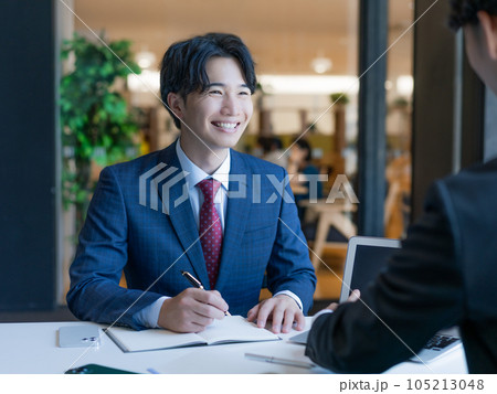 話を聞きながらメモをとる若いビジネスマン 話を聞きながらメモをとる若いビジネスマン 105213048
