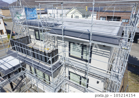 住宅リフォーム 外壁塗装と屋根の張替え作業中の家（空撮） 105214154