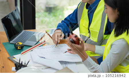 Civil engineers and architects discuss project construction together at office and holding walkie talkie 105216942