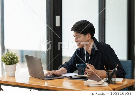 Young businessman drinking coffee and working using laptop and documents 105216952