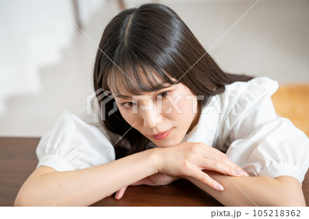 ウッドテーブルにもたれて寛ぐ若い女性 105218362