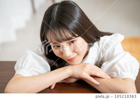 ウッドテーブルにもたれて寛ぐ若い女性 ウッドテーブルにもたれて寛ぐ若い女性 105218363