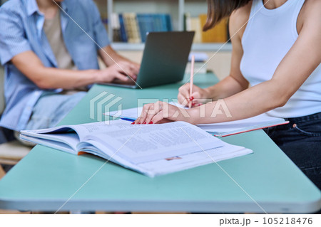 Close-up of female student's hand with pen notebook, male's hand typing on laptop Close-up of female student's hand with pen notebook, male's hand typing on laptop 105218476