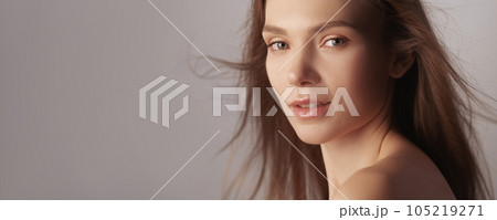Female care. Clean skin. Organic cosmetology. Woman with natural nude makeup radiant face bare shoulders flying hair isolated on beige background empty space. 105219271