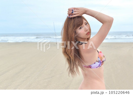 ビーチでポーズをとるビキニの水着を着た若い女性 ビーチでポーズをとるビキニの水着を着た若い女性 105220646