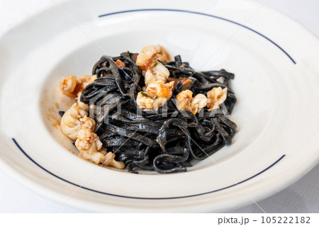 Serving portion of Italian squid ink pasta with shrimps served in white plate 105222182