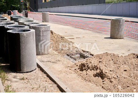 Laying concrete manholes and drain pipes for stormwater system. Connecting a trench drain to a concrete manhole structure at construction site. Construct stormwater and underground utilities Laying concrete manholes and drain pipes for stormwater system. Connecting a trench drain to a concrete manhole structure at construction site. Construct stormwater and underground utilities 105226042