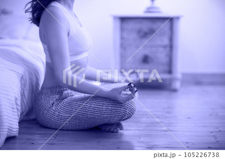 Smiling young brown haired woman in pajamas practicing yoga Smiling young brown haired woman in pajamas practicing yoga 105226738