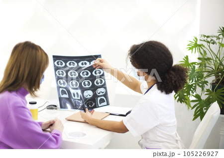 African-american woman doctor wearing face mask giving CD with X-ray image to female patient African-american woman doctor wearing face mask giving CD with X-ray image to female patient 105226927