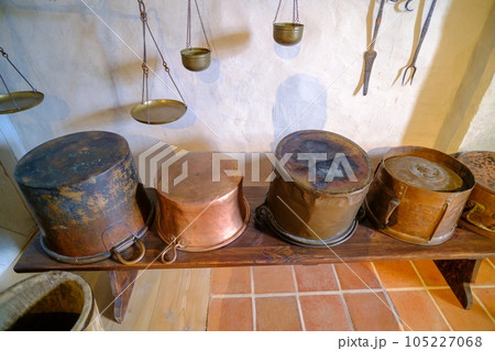 Ancient brass pots. Medieval kitchen metal cooking utensils. Interior of the kitchen of an old castle. Latvia Bauska Castle 105227068