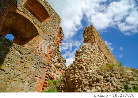 The walls of an old medieval castle. Collapsed walls preserved. Sightseeing object for tourists. Cracked wall texture with holes. Brick stone wall of building or house destroyed. Ancient buildings. The walls of an old medieval castle. Collapsed walls preserved. Sightseeing object for tourists. Cracked wall texture with holes. Brick stone wall of building or house destroyed. Ancient buildings. 105227076