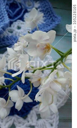 Blue, white crochet elements and orchid. Crochet texture, place for an inscription, adapted for mobile phone Blue, white crochet elements and orchid. Crochet texture, place for an inscription, adapted for mobile phone 105228105