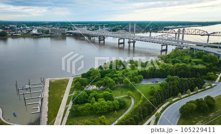 White truss, suspension bridges with rusty arch bridge on Ohio River near docks and greenery aerial 105229411
